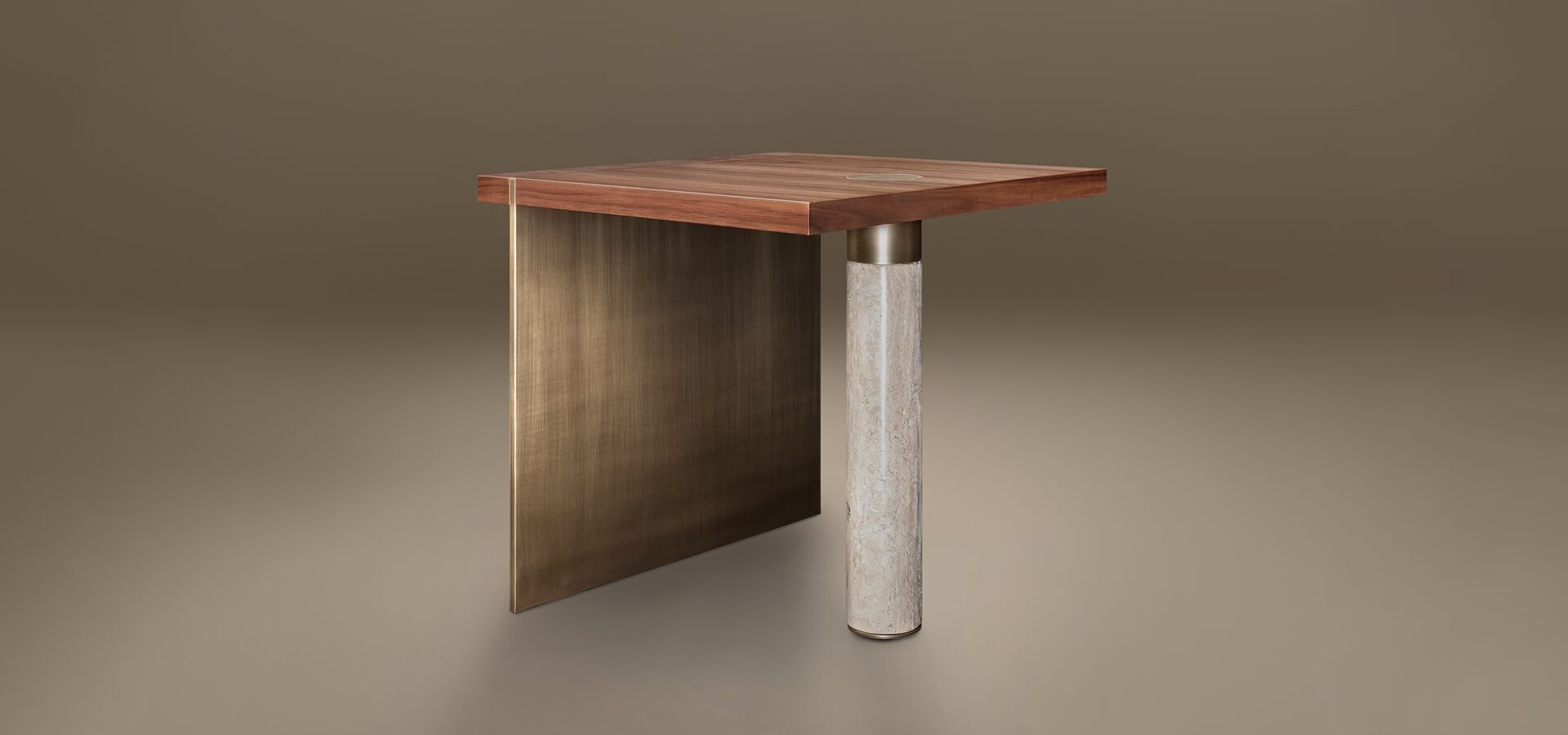 A luxury Lakewood Side Table by Porus Studio, featuring an asymmetrical design. The square top is crafted from Walnut wood with a small brass inlay. It is supported on one side by a wide, vertical panel of aged brushed brass and on the other by a single cylindrical pillar of beige travertine stone. The minimalist, sculptural piece is set against a neutral, warm-toned studio background.