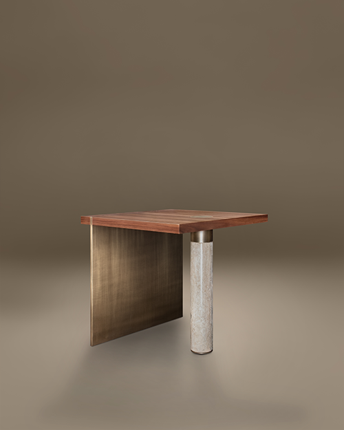 A luxury Lakewood Side Table by Porus Studio, featuring an asymmetrical design. The square top is crafted from Walnut wood with a small brass inlay. It is supported on one side by a wide, vertical panel of aged brushed brass and on the other by a single cylindrical pillar of beige travertine stone. The minimalist, sculptural piece is set against a neutral, warm-toned studio background.