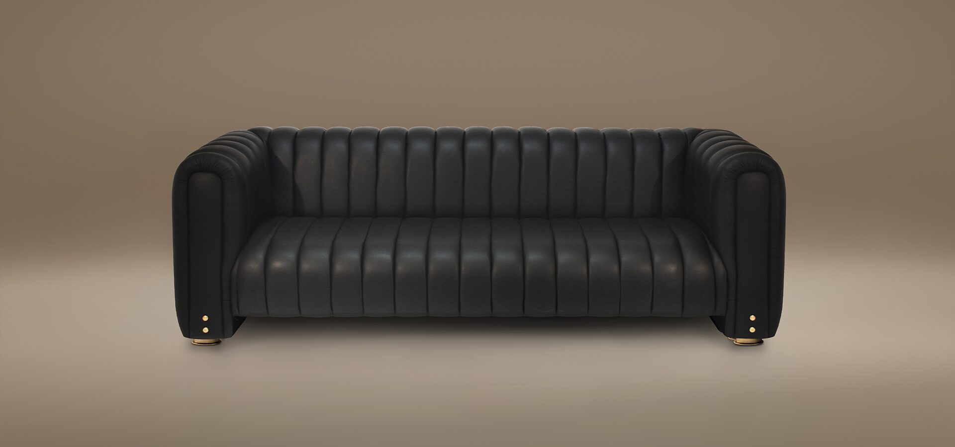A luxury Inglewood Sofa featuring a sophisticated design with continuous vertical tufting across the seat, backrest, and rounded armrests. Upholstered in premium black leather, the sofa is accented by small, polished brass stud details on the front of the arms and rests on subtle brass-finished cylindrical feet. Set against a minimalist, warm taupe studio background.