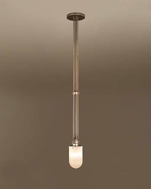 The Russell pendant lamp by Porus Studio, featuring an elegant industrial design crafted from brushed brass and alabaster. A cluster of long, slender brushed brass rods extends vertically from a circular ceiling canopy to a luminous, dome-shaped alabaster diffuser. A matching brass ring accents the central rods, highlighting the lamp's refined architectural silhouette against a neutral gradient background.
