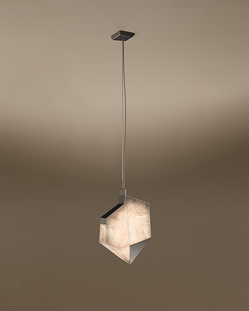 A contemporary Denali pendant lamp by Porus Studio, featuring an asymmetrical, geometric shade with sharp crystalline angles. The lamp glows with a warm, textured alabaster-like finish, framed by dark metallic edges, suspended from a slim cable against a soft brown gradient background.
