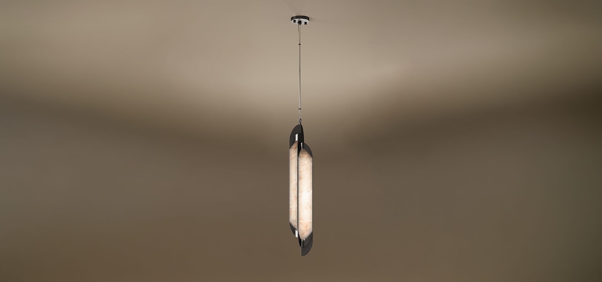 A vertical Glacier I pendant lamp by Porus Studio, featuring a slender, elongated design. A glowing center made of textured, warm-toned alabaster is held between two dark, curved metallic plates that overlap slightly. The fixture is suspended from a single thin cable set against a soft, neutral gradient background.
