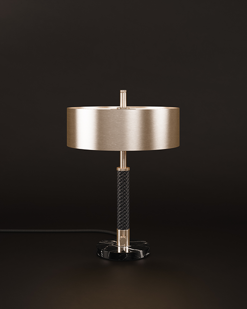 Front view of the Chicago table lamp set against a dark brown background, where cool stainless steel and solid marble are balanced by a central braided leather element, creating a tactile contrast between cold metal and warm artisanal texture.