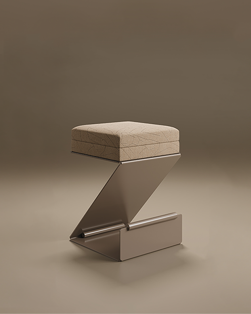 Lombard Bar Stool, showcasing its architectural Z-shaped cantilever design. The stool is crafted from a continuous sheet of metal with a integrated cylindrical footrest at the base. The square seat is thick and upholstered in a beige textured fabric featuring a subtle, etched geometric pattern. Set against a minimalist, warm brown studio background with soft floor reflections.
