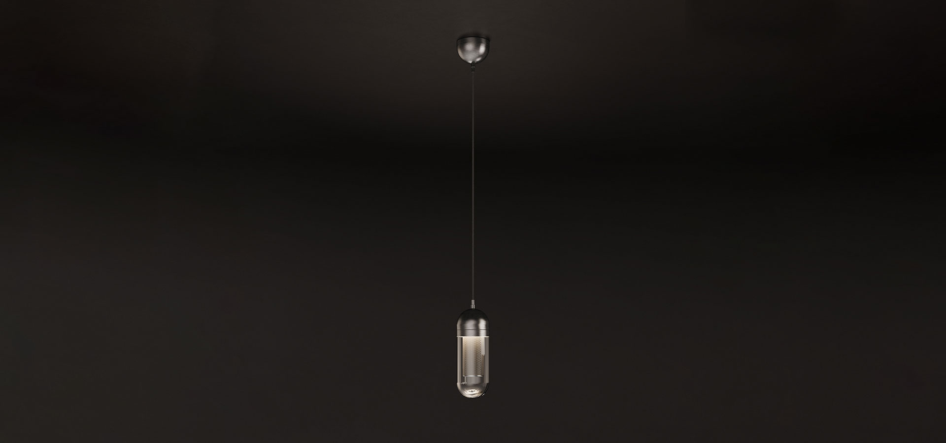 A professional studio photograph of the Denver I Pendant Lamp by Porus Studio, shown hanging and illuminated against a dark background. The light glows from within a lacquered perforated stainless steel cylindrical core, which is encased in a rounded clear glass capsule. The internal light source creates a sophisticated diffused glow as it passes through the metal perforations, casting a textured pattern and highlighting the sleek stainless steel upper structure. The light emits a focused downward beam while creating a soft, ambient brilliance through the glass body.
