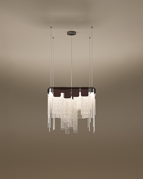 The Frostlight pendant lamp by Porus Studio, featuring a dramatic chandelier design inspired by icy formations. A rectangular metallic frame supports a cascading arrangement of textured, frosted glass panels and slender metallic rods of varying lengths, creating a shimmering tiered effect. The top is accented by dark decorative tabs, and the fixture is suspended from the ceiling by multiple thin cables against a soft, neutral gradient background.
