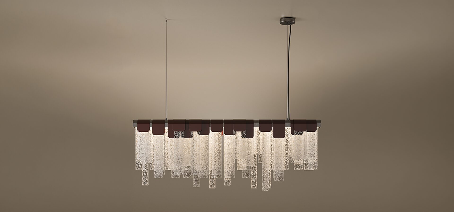 Frostlight Suspension Lamp The Frostlight suspension lamp, a sophisticated linear lamp featuring a row of textured, frosted glass panels in varying lengths. The glass slabs are held by elegant dark leather or metal clasps along a horizontal bar, creating a rhythmic, shimmering effect that resembles hanging ice or frost. The fixture is suspended by two thin cables against a warm, neutral background, blending contemporary design with organic textures.