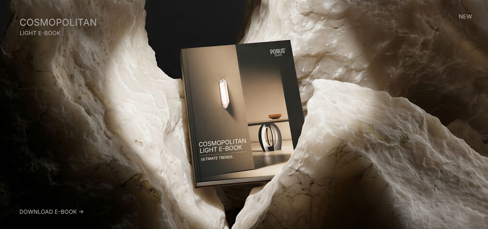 A high-end design e-book titled "Cosmopolitan Light" by Porus Studio is displayed amidst a dramatic, organic landscape of raw, glowing alabaster rock. The lighting emphasizes the texture of the stone, reflecting the book's focus on materiality and atmospheric lighting trends.