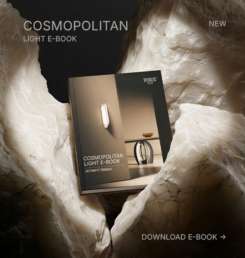 A high-end design e-book titled "Cosmopolitan Light" by Porus Studio is displayed amidst a dramatic, organic landscape of raw, glowing alabaster rock. The lighting emphasizes the texture of the stone, reflecting the book's focus on materiality and atmospheric lighting trends.