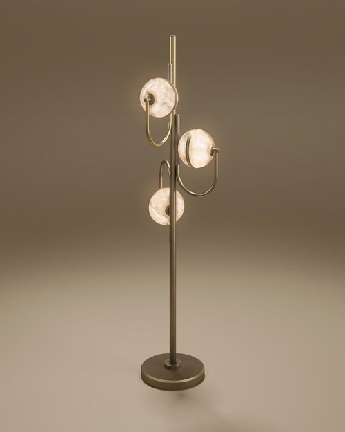 Oculus floor lamp in aged brushed brass with three illuminated alabaster discs, each held by a curved U-shaped arm along a slim central stem, on a round base against a soft taupe backdrop.