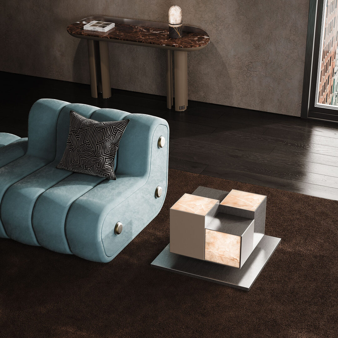 4 stunning living room pieces. Hudson side table with illuminated alabaster panels in a living room setting, placed next to the dakota sofa upholstered in blue fabric and the beverly console, with the russel table lamp on top. The pieces shines next to other living room pieces.